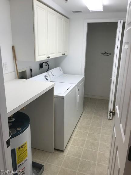 washroom with hookup for an electric dryer, cabinets, light tile floors, and washer and clothes dryer