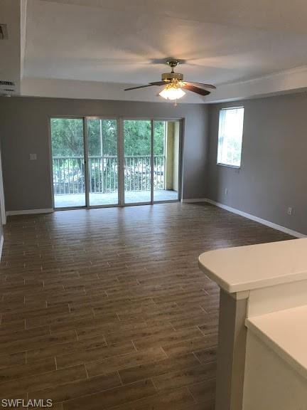 empty room with plenty of natural light, dark hardwood / wood-style floors, and ceiling fan