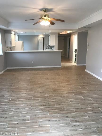 kitchen with ceiling fan, kitchen peninsula, white cabinetry, and white fridge