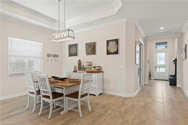 dining area with a raised ceiling and ornamental molding