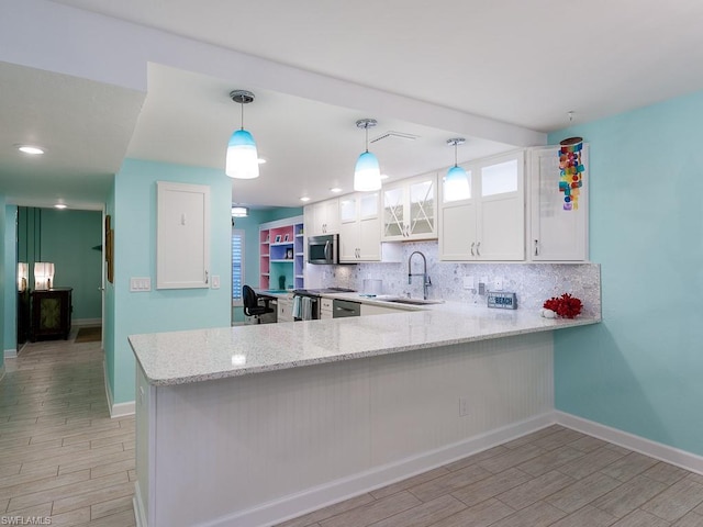 kitchen with decorative light fixtures, kitchen peninsula, white cabinetry, and backsplash