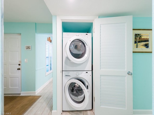 clothes washing area with light hardwood / wood-style floors and stacked washer and clothes dryer