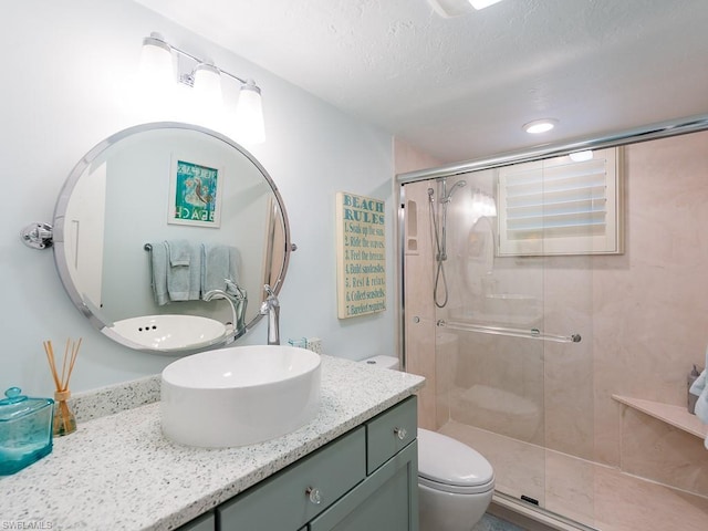 bathroom with a textured ceiling, an enclosed shower, vanity, and toilet