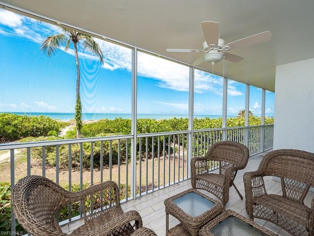 sunroom / solarium featuring ceiling fan and a water view