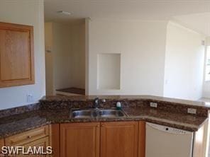 kitchen with white dishwasher, dark stone countertops, and sink