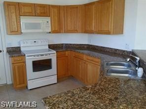 kitchen with white appliances, sink, and light tile floors