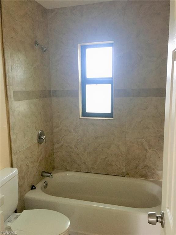 bathroom with toilet and tiled shower / bath combo