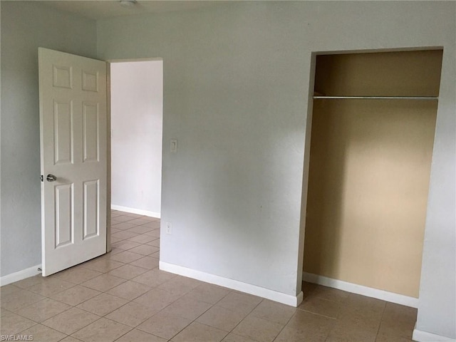 unfurnished bedroom featuring a closet and light tile floors