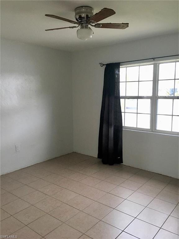 tiled empty room featuring ceiling fan