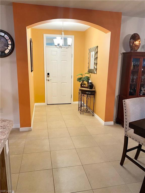 tiled foyer entrance featuring an inviting chandelier