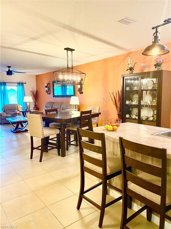 tiled dining area with ceiling fan with notable chandelier