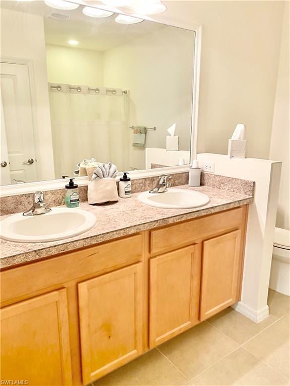 bathroom featuring double sink vanity, tile floors, and toilet