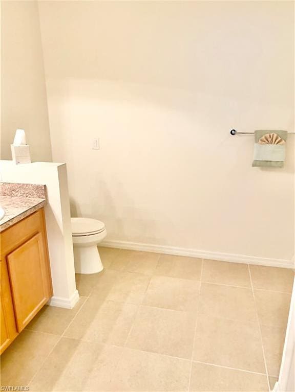 bathroom with toilet, tile flooring, and vanity