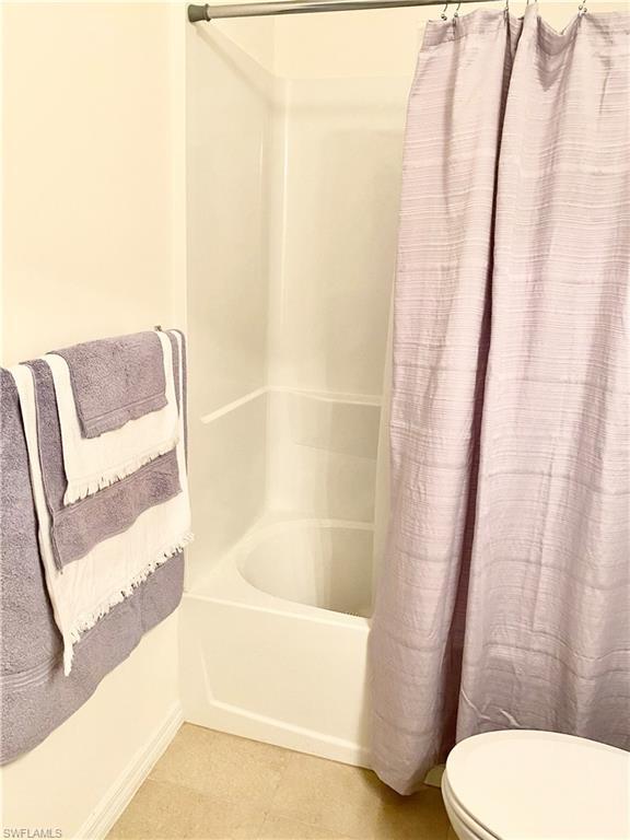 bathroom featuring shower / tub combo, tile floors, and toilet