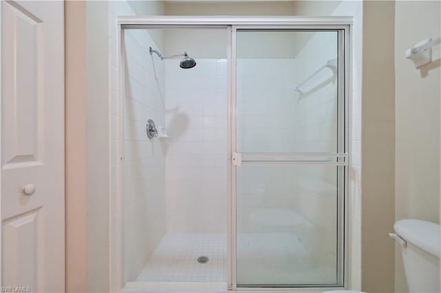 bathroom featuring a shower with shower door and toilet