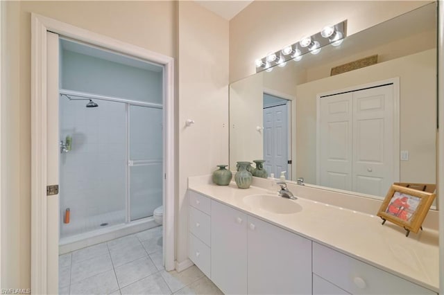 bathroom featuring toilet, tile floors, a shower with shower door, and vanity with extensive cabinet space