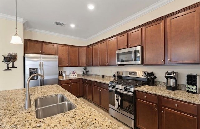 kitchen featuring sink, light stone counters, hanging light fixtures, ornamental molding, and appliances with stainless steel finishes