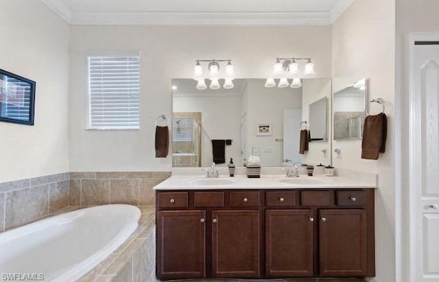 bathroom with tiled bath, large vanity, dual sinks, and crown molding