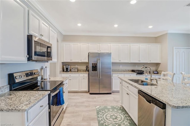 kitchen with an island with sink, stainless steel appliances, white cabinetry, and sink