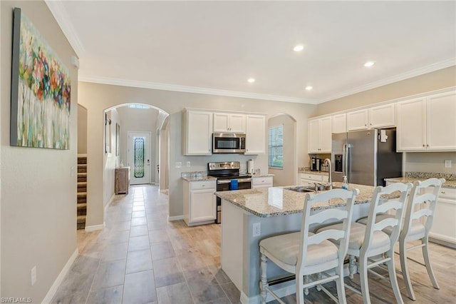 kitchen featuring white cabinetry, stainless steel appliances, a kitchen island with sink, and light stone countertops