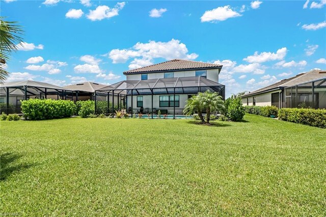 rear view of property with a lawn and a lanai