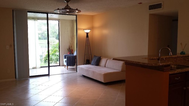 sitting room with a textured ceiling, sink, and light tile floors