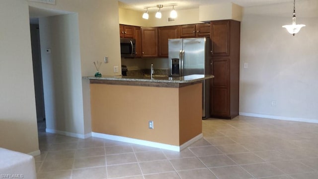 kitchen with pendant lighting, stainless steel appliances, light tile floors, dark stone counters, and track lighting