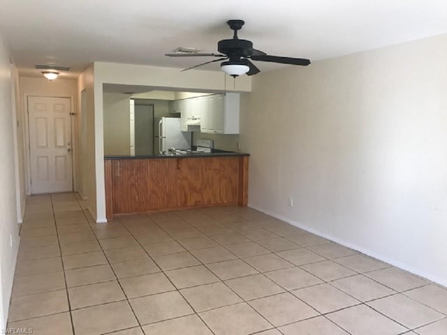 kitchen featuring stove, light tile floors, ceiling fan, and white fridge