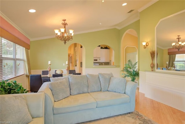 living room featuring crown molding, an inviting chandelier, and light hardwood / wood-style floors