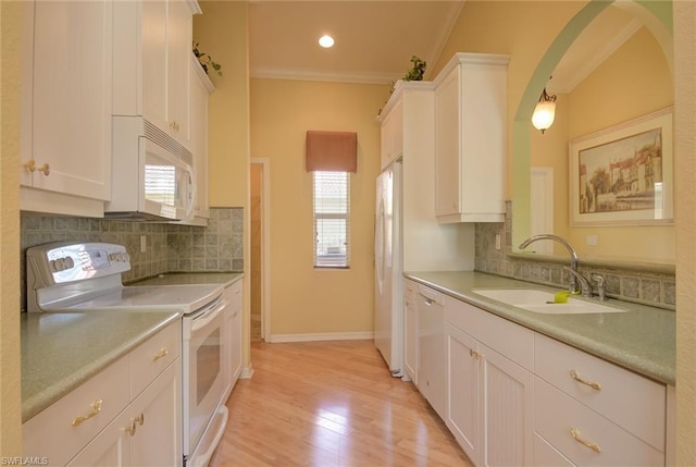 kitchen with ornamental molding, light hardwood / wood-style flooring, white appliances, white cabinets, and backsplash