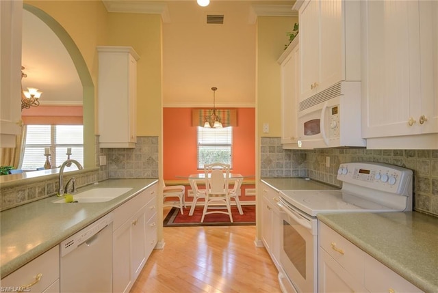 kitchen with hanging light fixtures, white cabinetry, white appliances, light wood-type flooring, and a chandelier