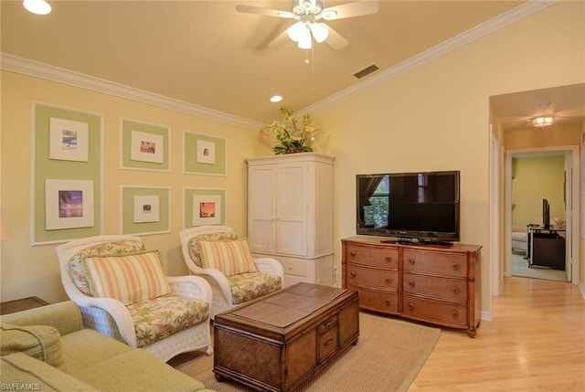 living room with ornamental molding, ceiling fan, and light wood-type flooring