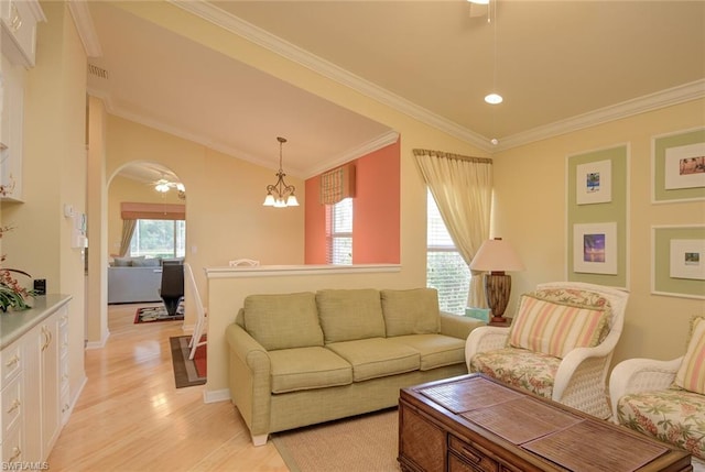 living room with ornamental molding, light hardwood / wood-style flooring, ceiling fan with notable chandelier, and a wealth of natural light