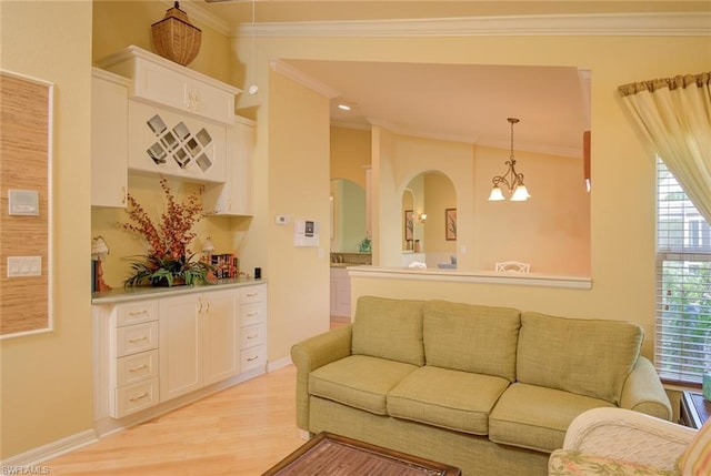 living room featuring ornamental molding, a notable chandelier, and light hardwood / wood-style flooring