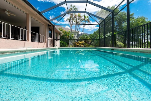 view of pool with glass enclosure and ceiling fan