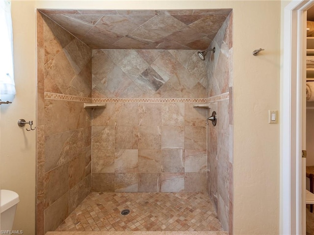 bathroom featuring toilet and a tile shower