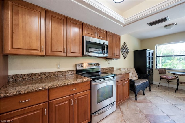 kitchen with dark stone counters, stainless steel appliances, and light tile floors