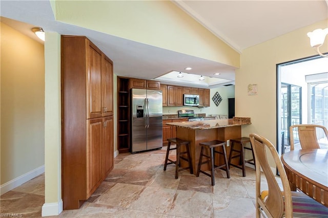 kitchen with appliances with stainless steel finishes, stone counters, kitchen peninsula, and light tile flooring