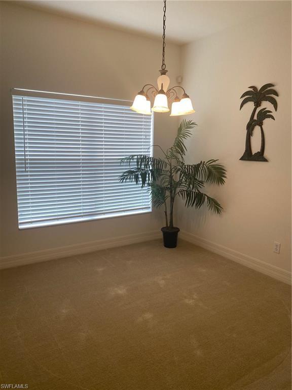 carpeted spare room with an inviting chandelier