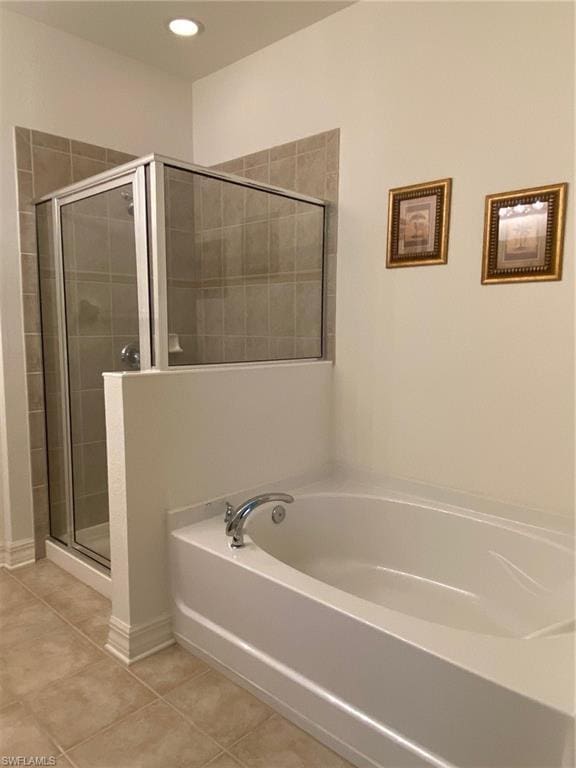 bathroom featuring shower with separate bathtub and tile floors