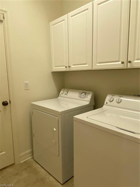 washroom featuring cabinets, washer and dryer, and light tile floors