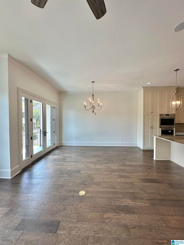 unfurnished living room featuring ceiling fan with notable chandelier and dark hardwood / wood-style flooring