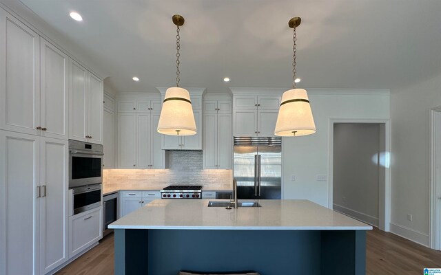 kitchen with sink, decorative light fixtures, a kitchen island with sink, hardwood / wood-style flooring, and stainless steel appliances