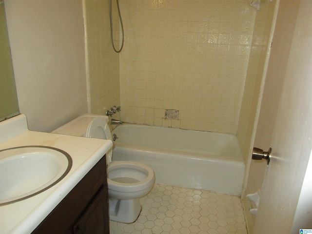 full bathroom with tiled shower / bath, toilet, tile floors, and vanity