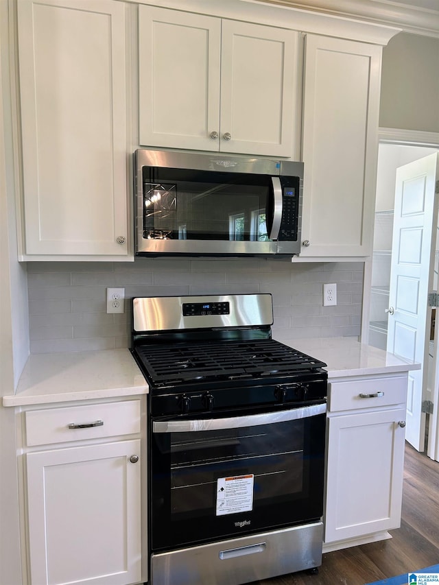 kitchen with white cabinetry, light stone countertops, dark wood-type flooring, tasteful backsplash, and appliances with stainless steel finishes