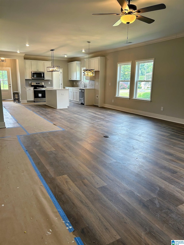 unfurnished living room with crown molding, dark wood-type flooring, and a wealth of natural light