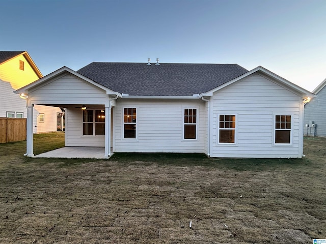 back house at dusk with a lawn and a patio area