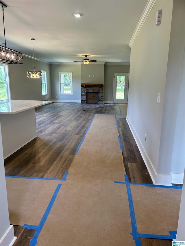 unfurnished living room with plenty of natural light, dark hardwood / wood-style floors, and ornamental molding