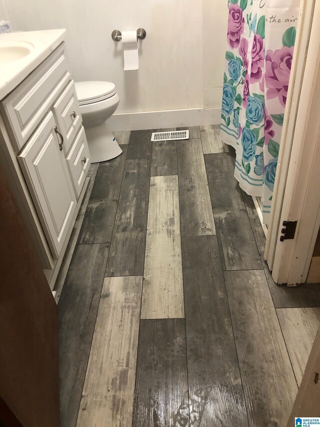 bathroom with hardwood / wood-style flooring, toilet, and vanity