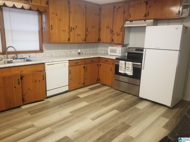 kitchen featuring tasteful backsplash, white appliances, sink, and light wood-type flooring